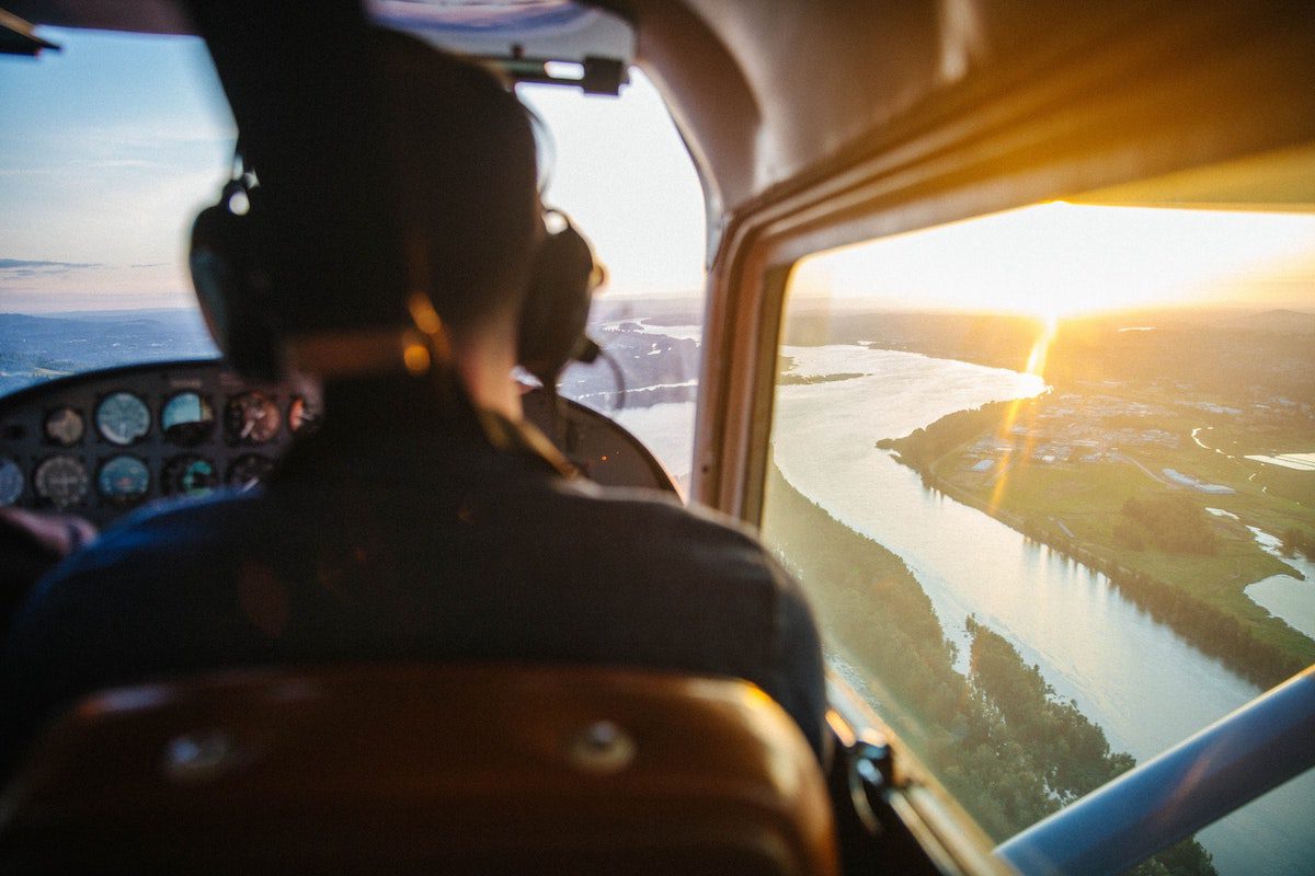 View from behind a pilot of a small plane with a river landscape out the window. Jobs That Require Travel And Pay Well