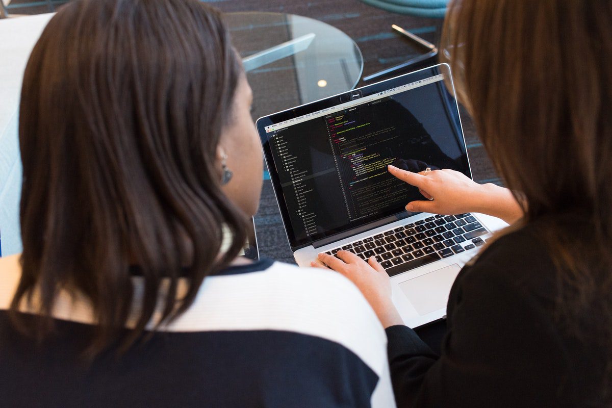 Two women looking at a code on a laptop. Software Engineering Processes