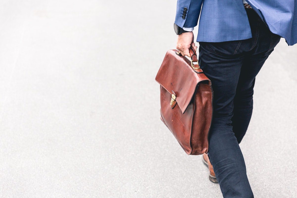 A man in a suit holding a brown laptop bag. Google Benefits