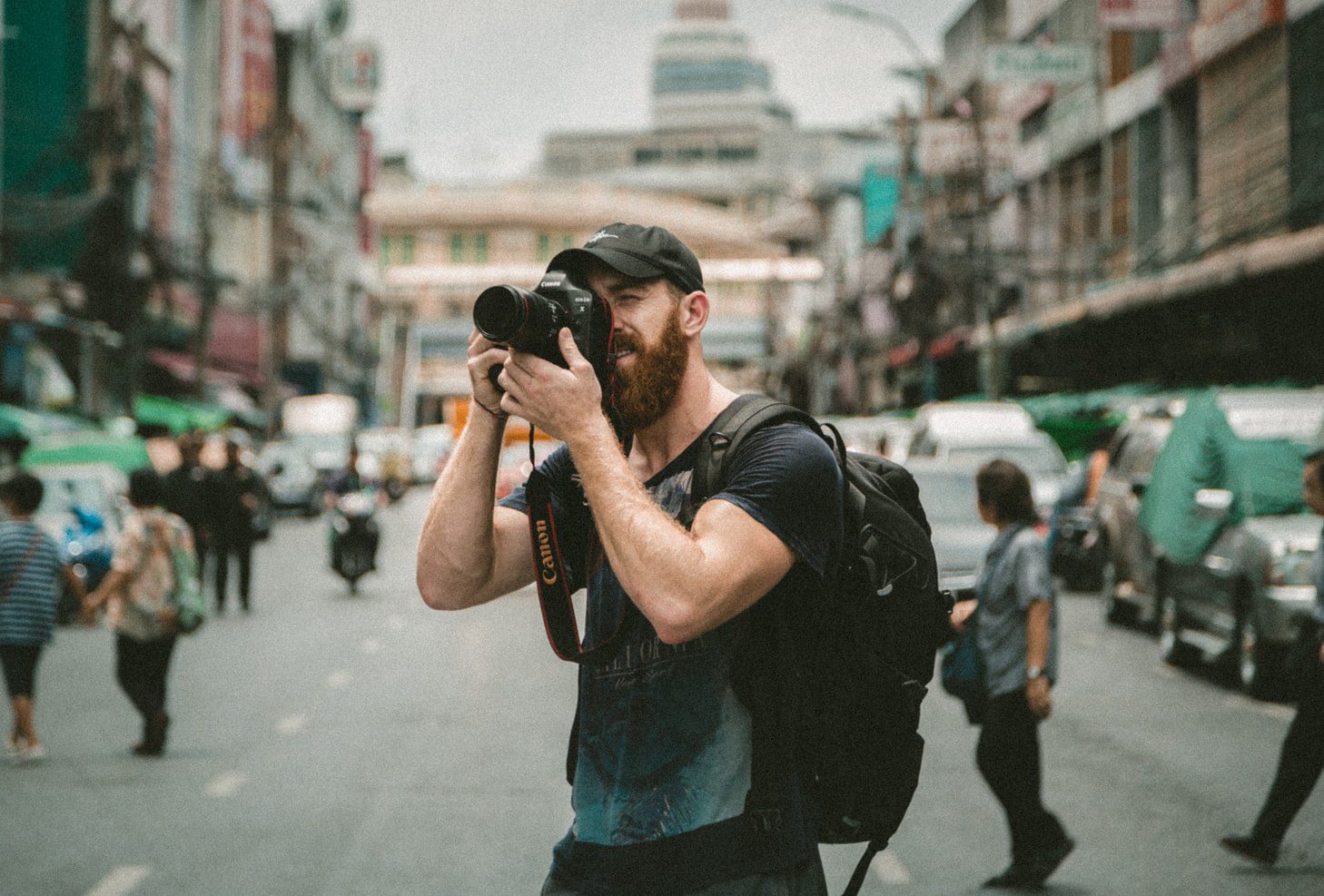 A man taking a picture with a camera in the middle of a street. Side Hustles For Men