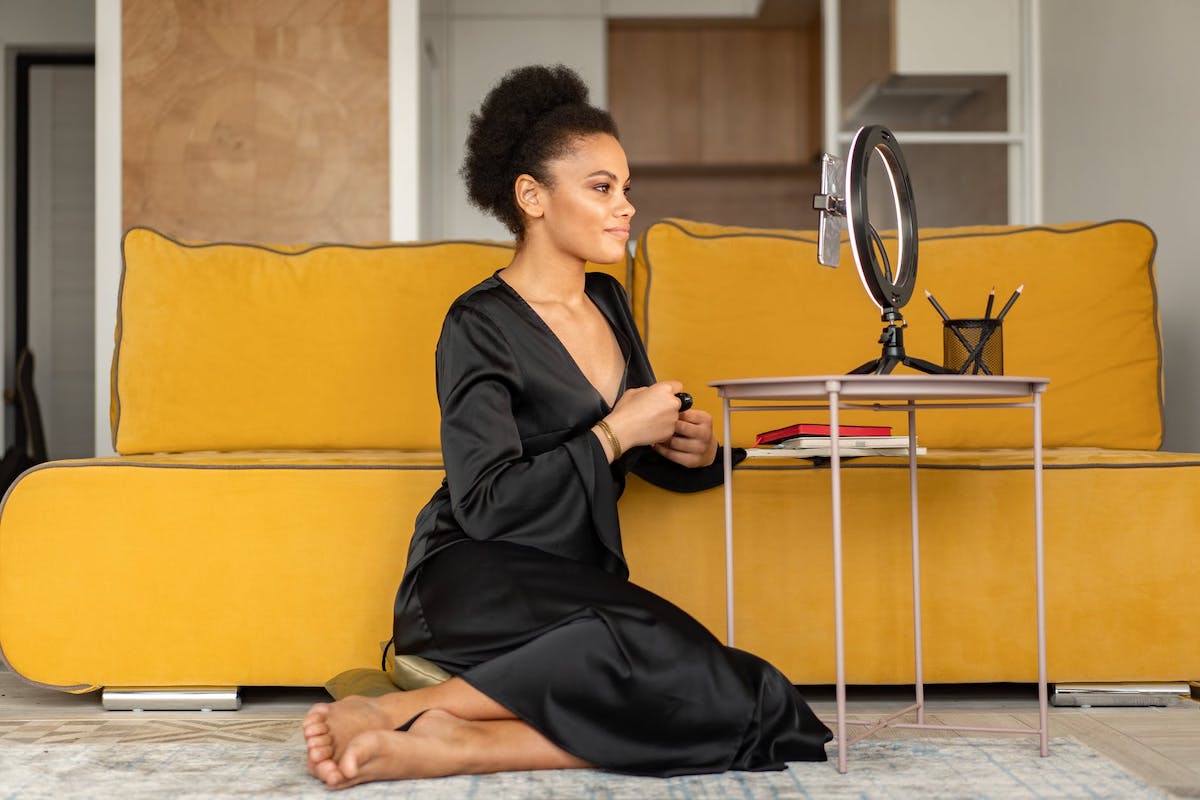 A woman creating online content with a phone and a ring light. Side Hustles for Software Engineers