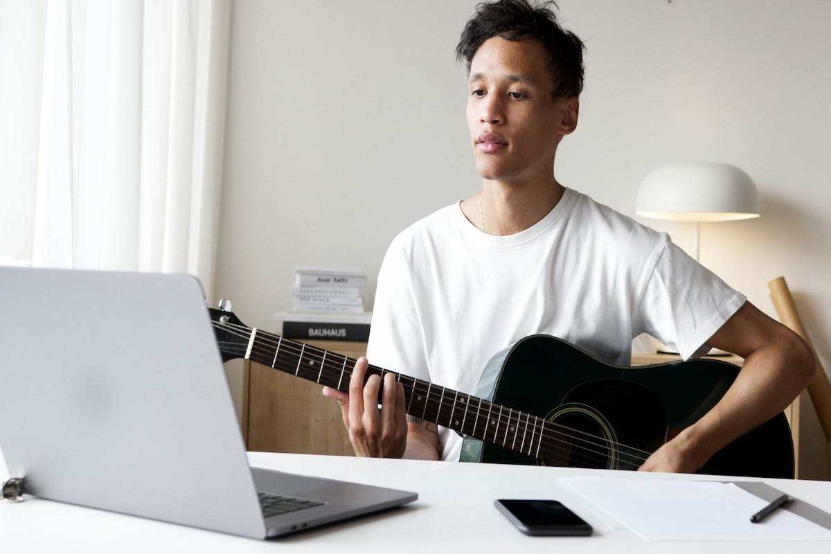 Teenage boy playing guitar and filming with laptop Side Hustles For Teens
