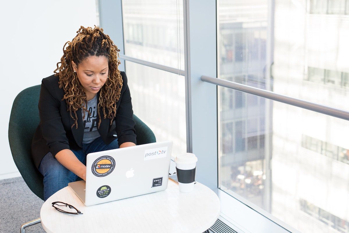 a woman sitting in front of a desk typing on a MacBook Pro near the window Types of Web Development Jobs