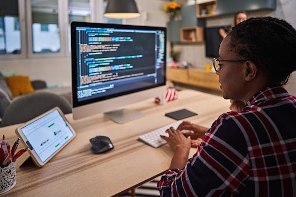 A person types code into a software program on their desktop computer Master In Information Technology Scholarships 