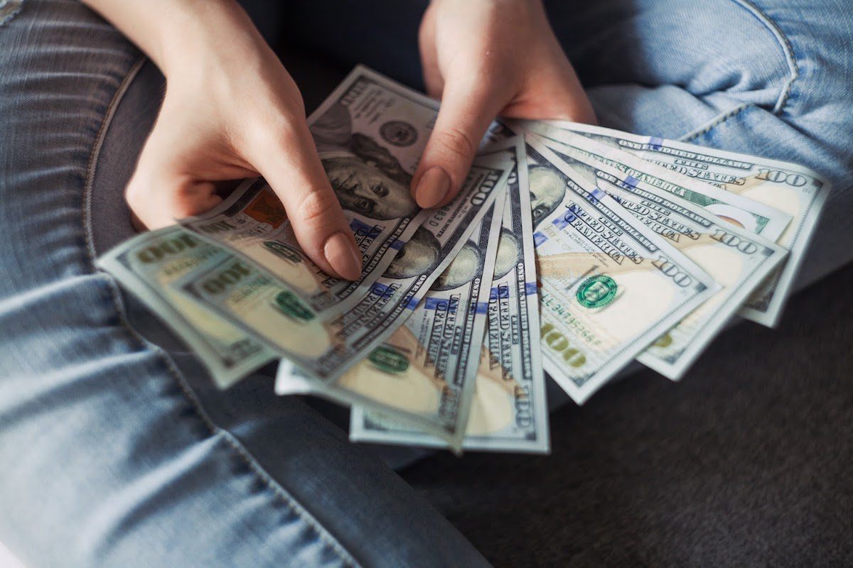 A woman holding a couple of hundred dollar bills. 