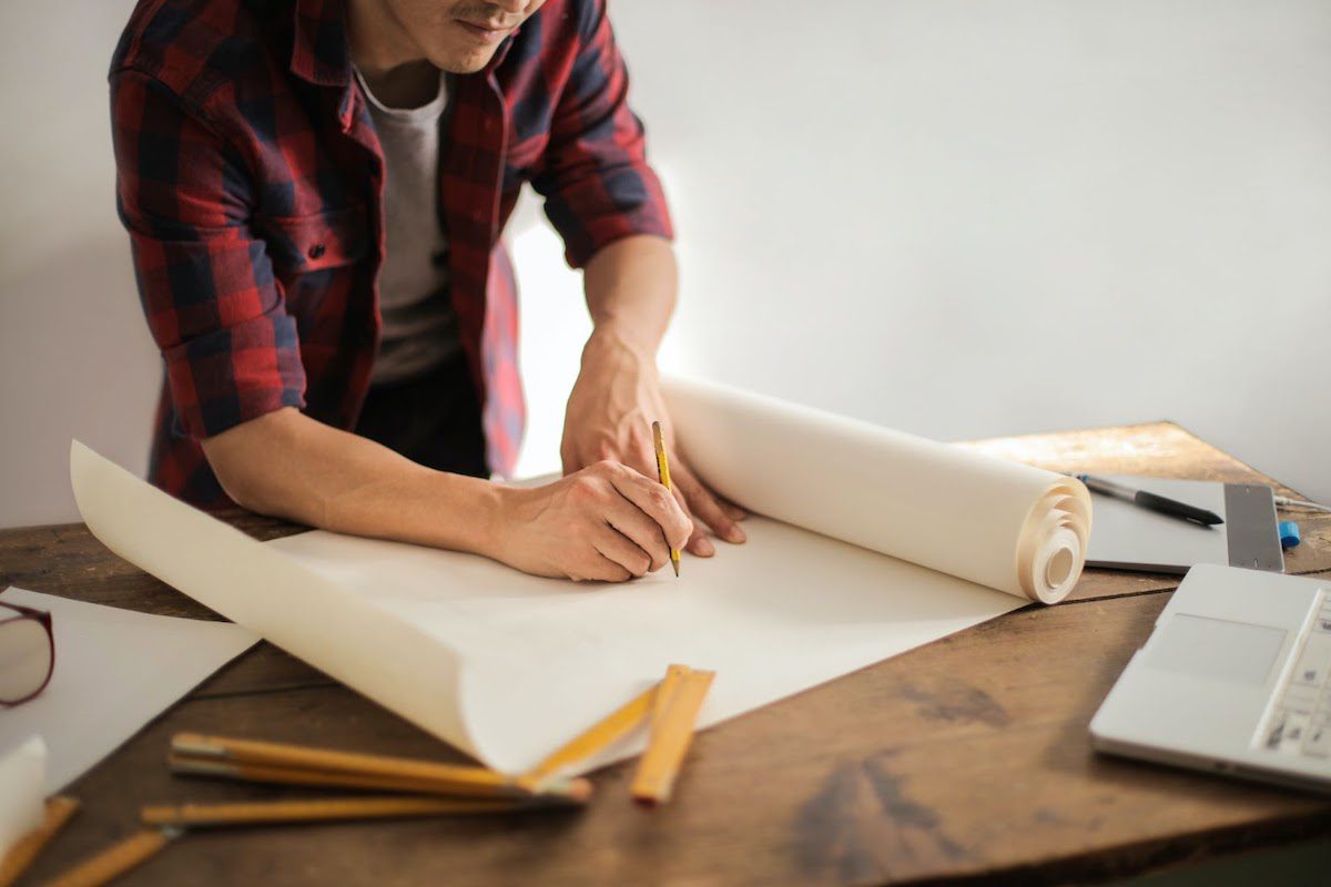 Artist working on a client project for his creative business and drawing on a canvas on the table