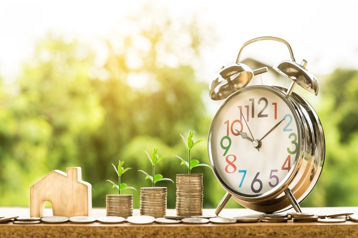 A clock placed next to columns of coins to indicate growth over a period of time