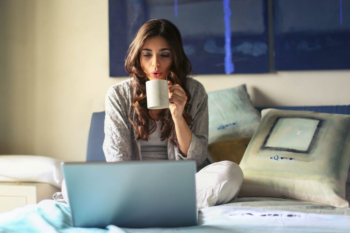 a woman working with her laptop while drinking a cup of coffee