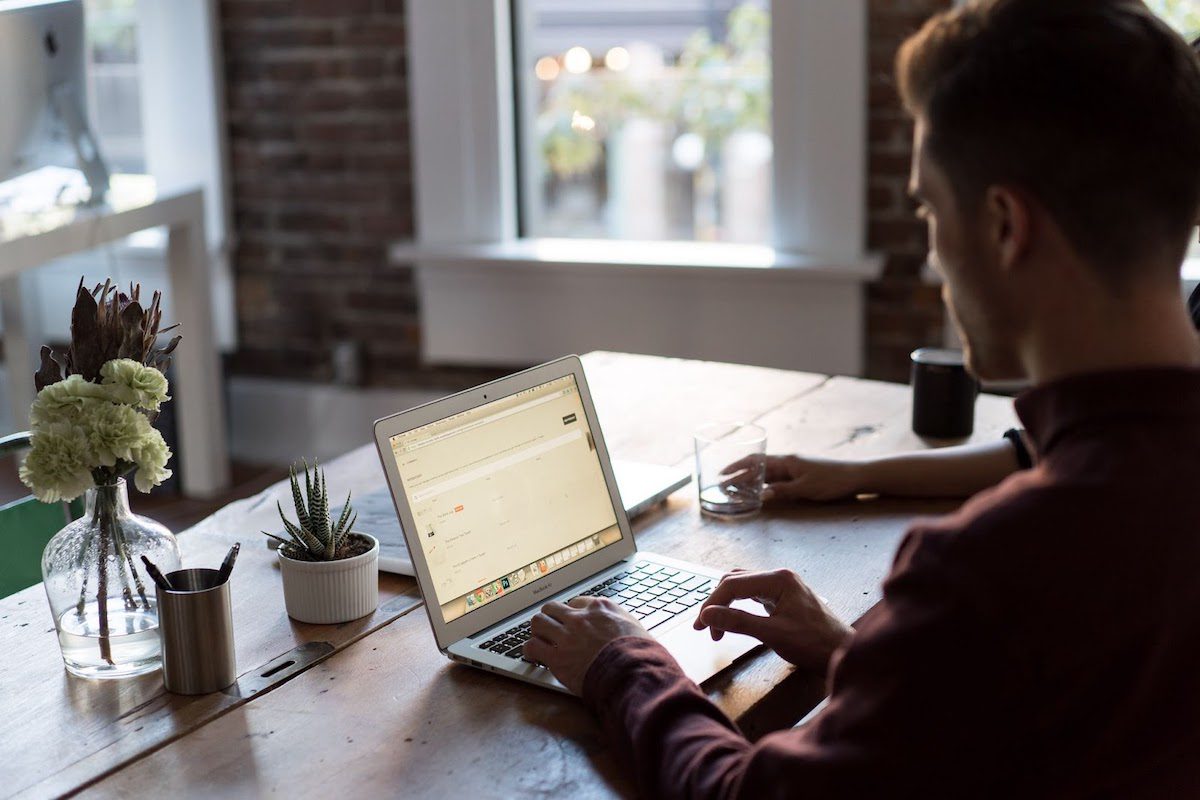 A man sitting at a table using his laptop