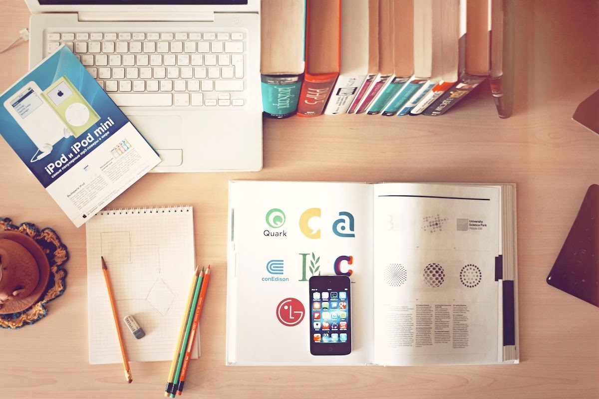 A book with various logos and other design essentials laid out on a table Jobs That Use Graphic Design