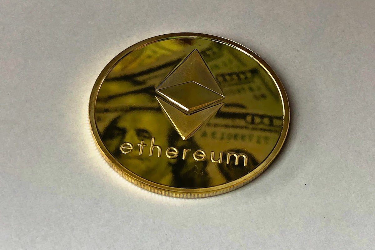 A gold coin with the Ethereum name and emblem engraved on it.
