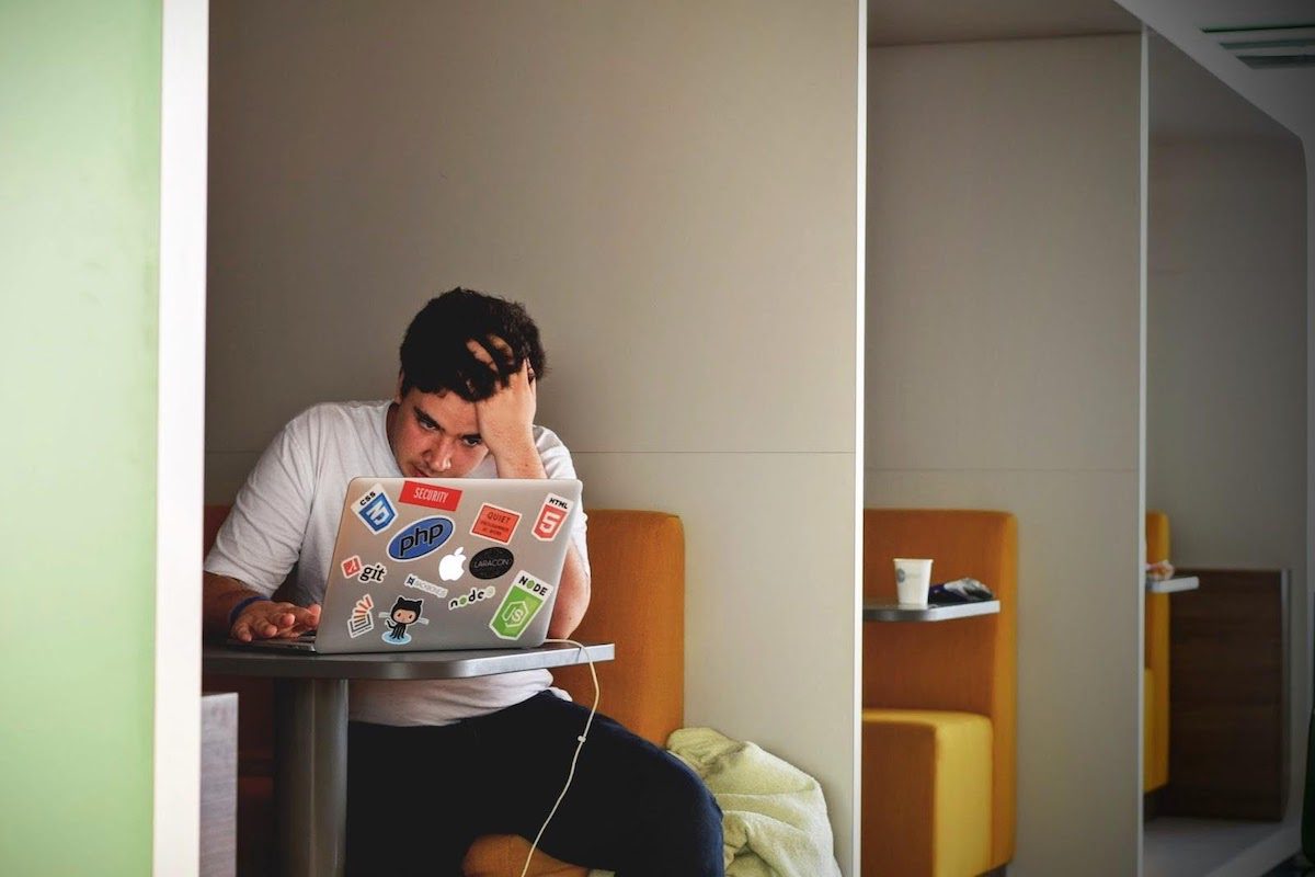 A college student in a study area working on making an app using his computer
