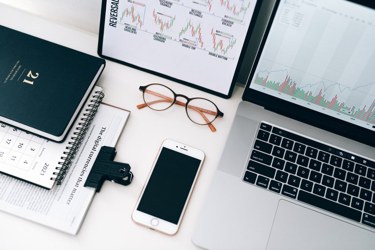 Laptop with financial statistics beside eyeglasses and smartphone. A Day In The Life Of A Financial Advisor