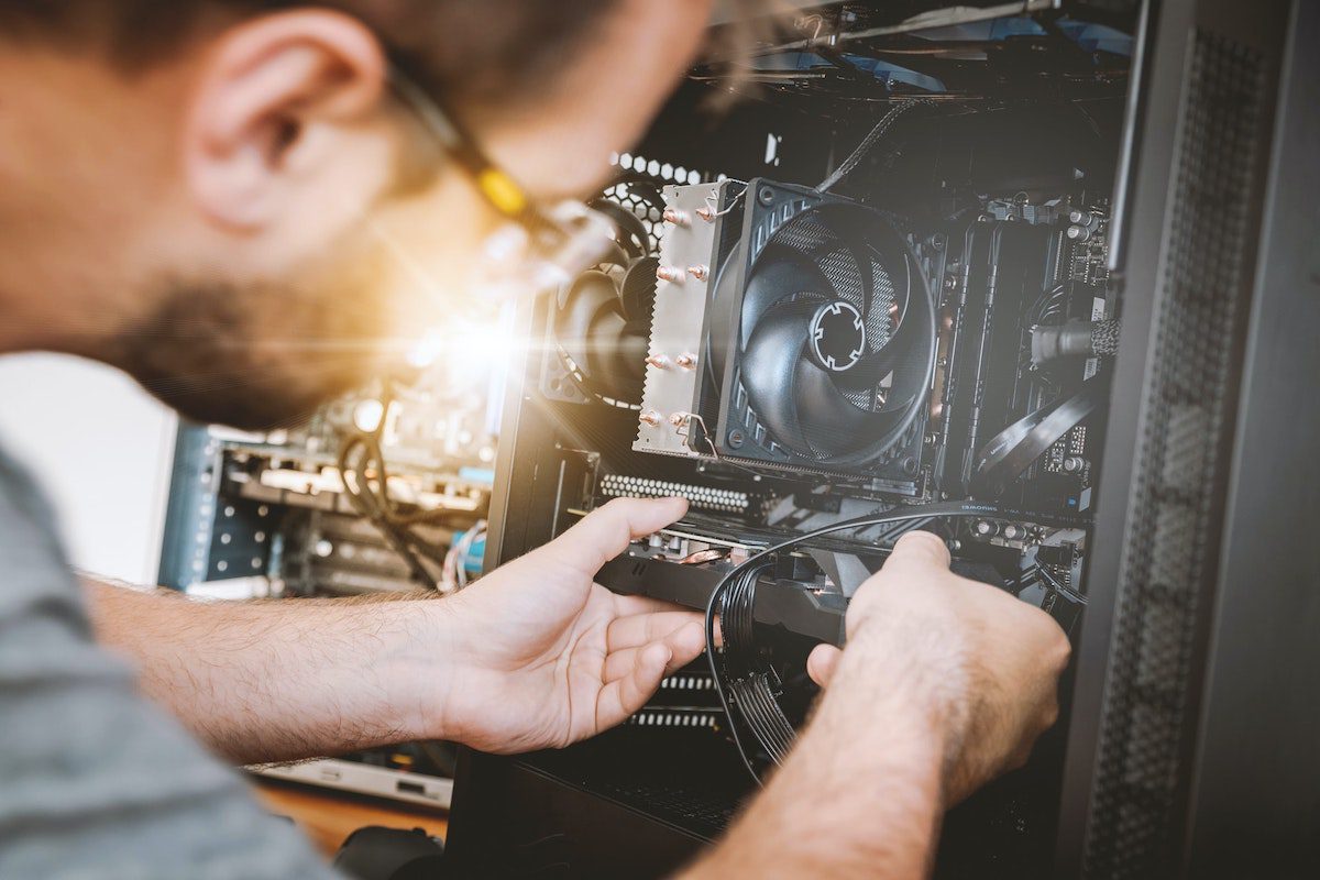 A person wearing a gray t-shirt and holding black and silver computer hardware equipment. A Day In The Life Of A Computer Engineer