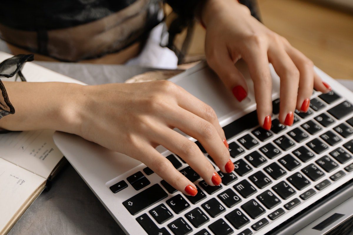 Person with manicured red nails using a laptop. A Day In The Life Of A Medical Coder