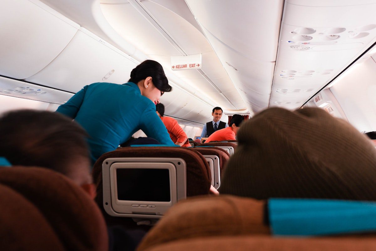 Airline crew members attending to passengers on a plane. A Day In The Life Of A Flight Attendant