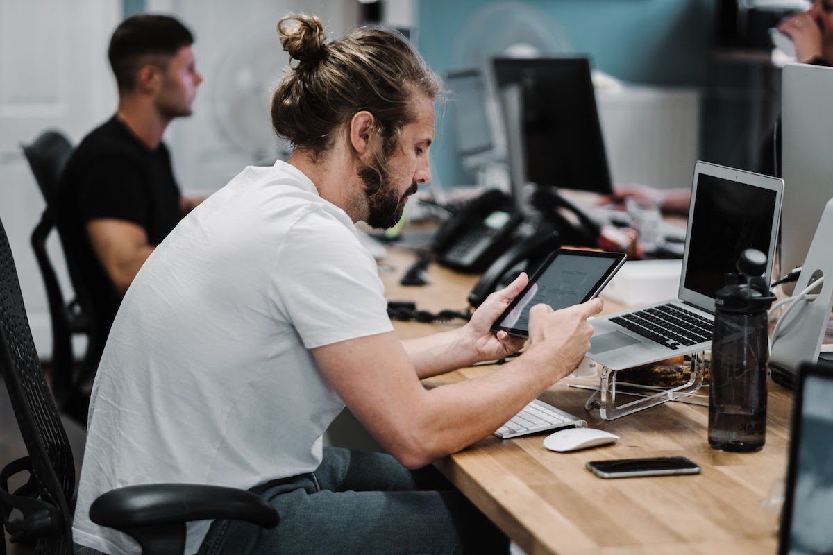 A man holding a lit iPad in a shared office space