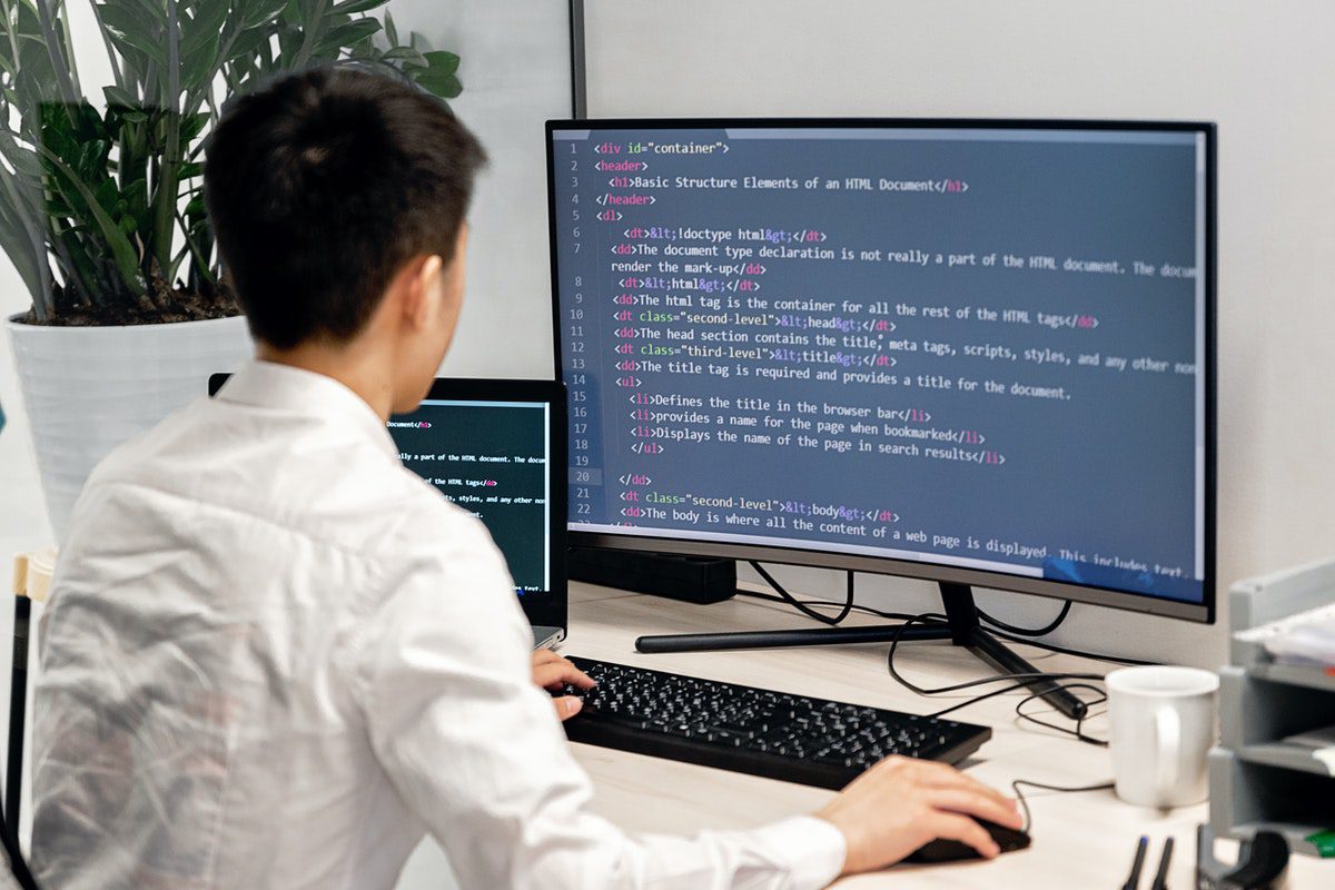 A web developer seated in front of an office computer displaying lines of code. Is Python Worth Learning