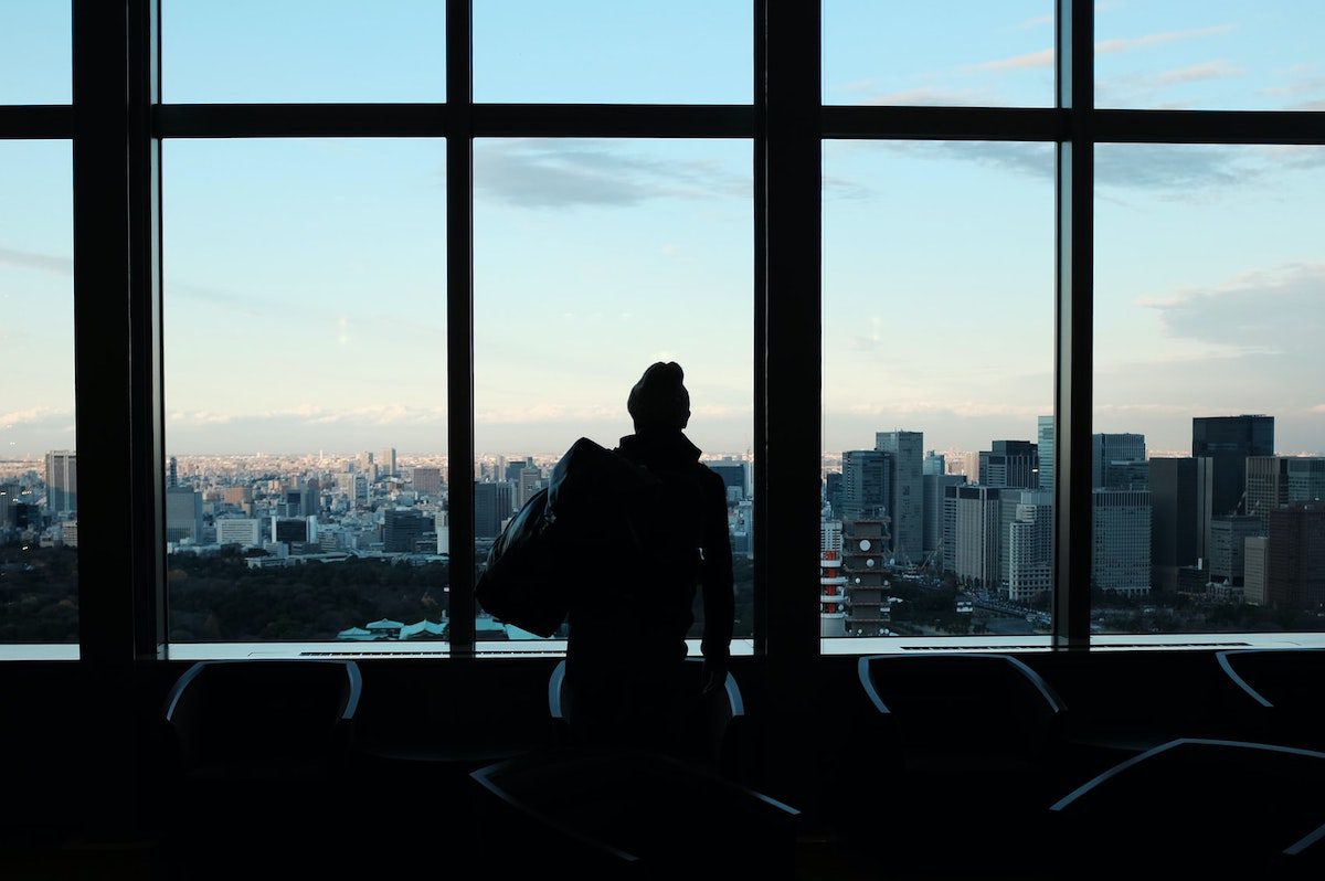 A person looking out of a window at an airport. Jobs That Require Travel