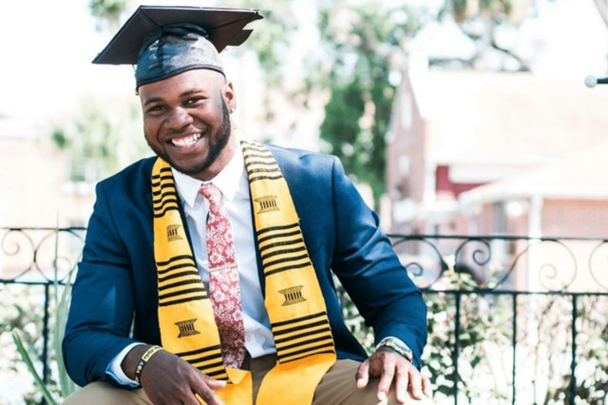 A man smiling while wearing a graduation cap.
