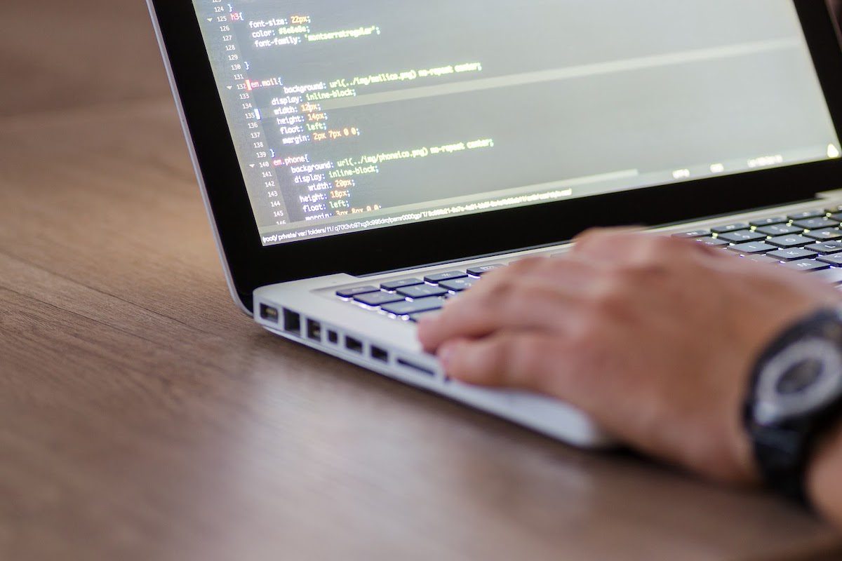 A person working on a computer with codes on the screen.