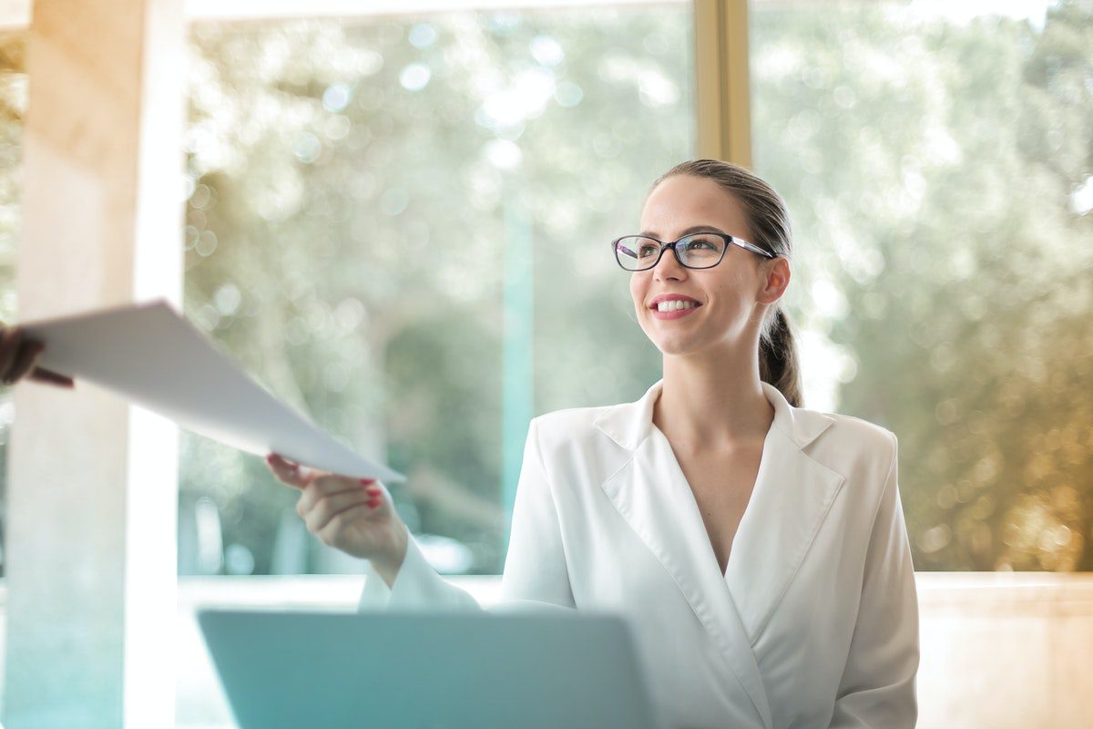 A lady on a desk with a computer receiving some papers. Jobs That Require No Experience But Pay Well