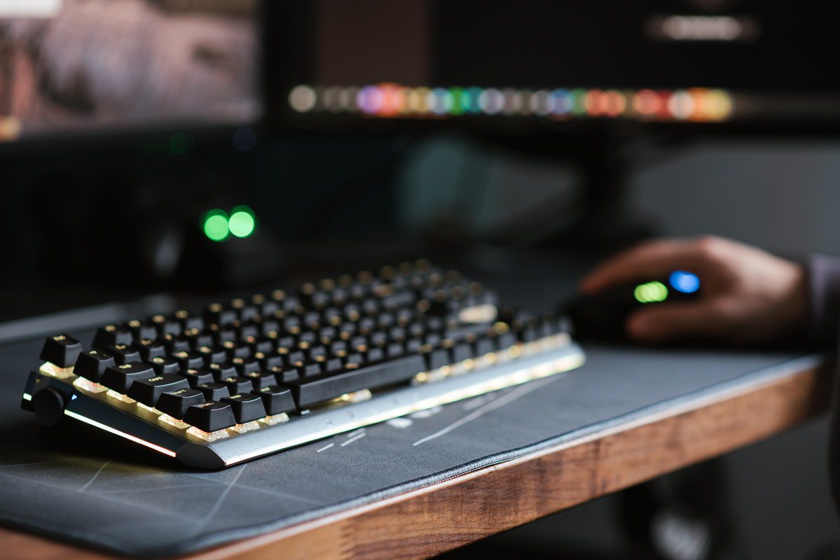 A man holding a mouse next to a keyboard on a desk. Who Uses Ajax?