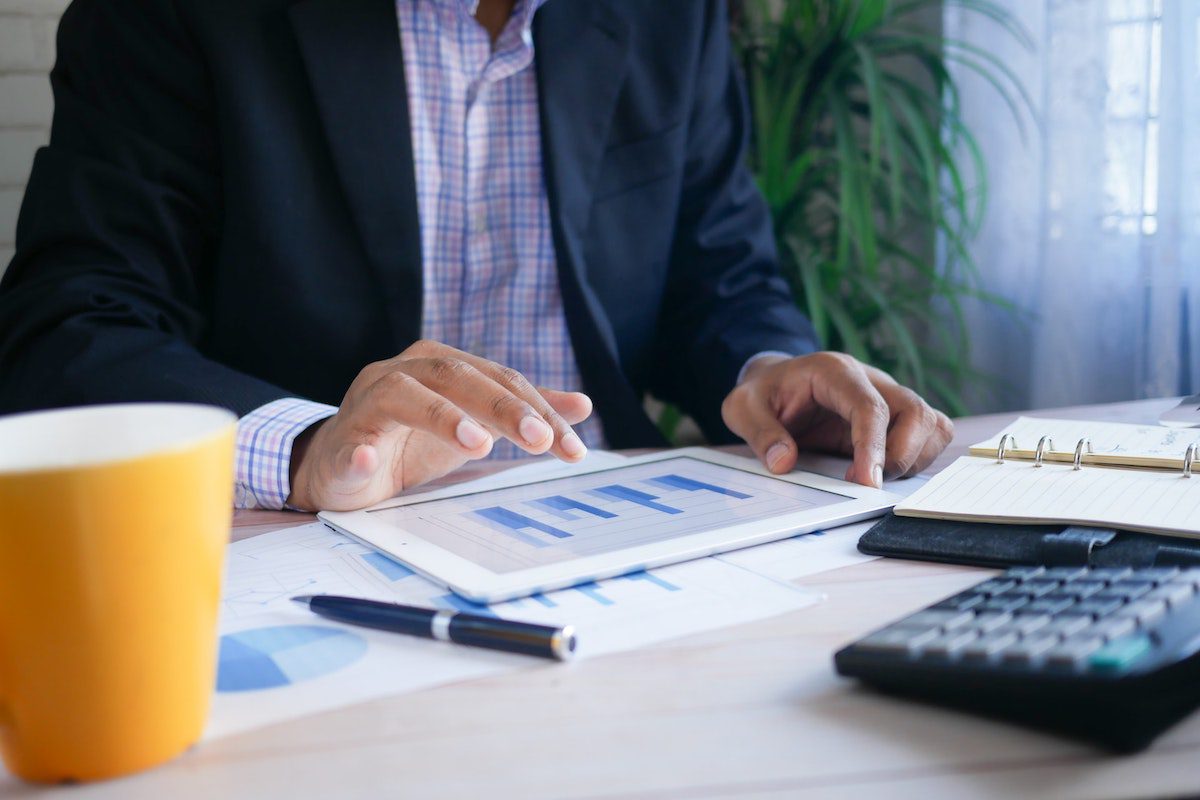 A businessman sitting at a desk and analyzing critical dates on a tablet. Who Uses Excel?