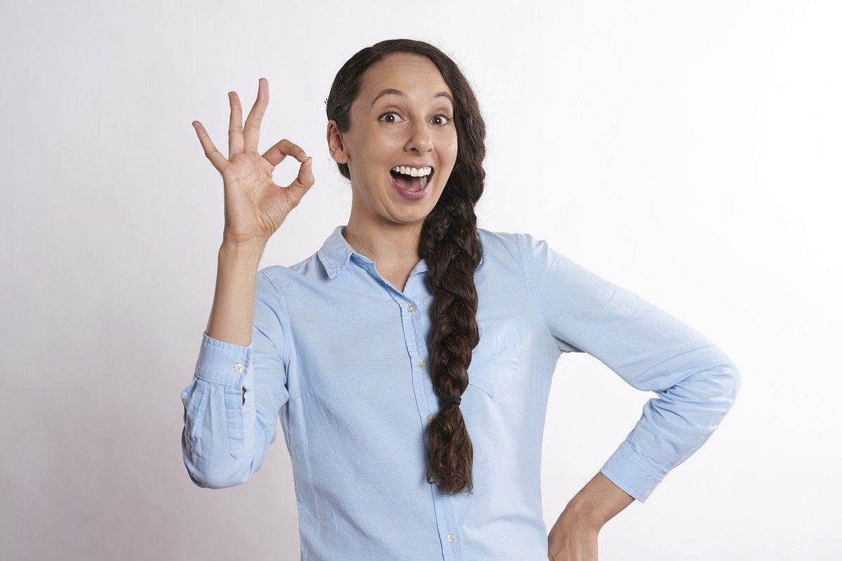 A woman smiling while holding up an okay sign. Who Uses Php?