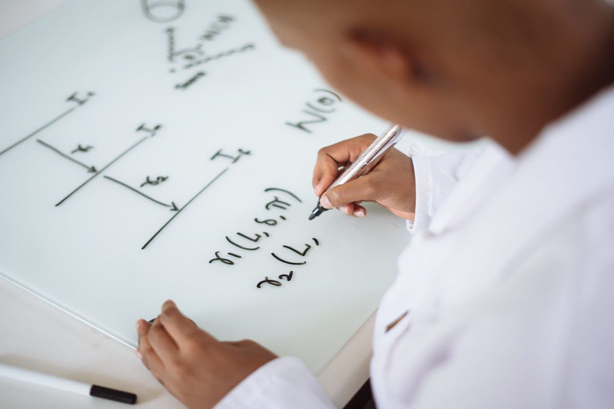 A person deriving a formula on a whiteboard 