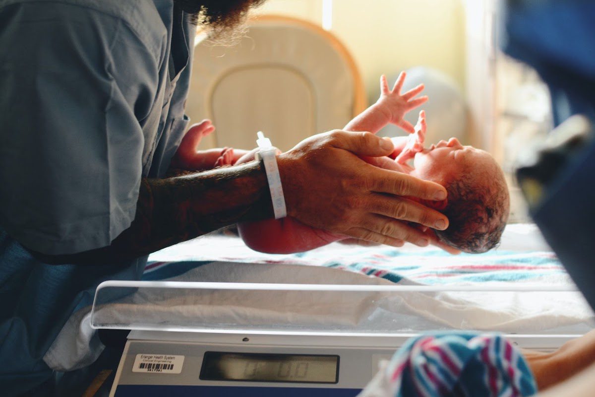 A nurse setting a newborn baby down on a scale Accelerated Nursing Degrees
