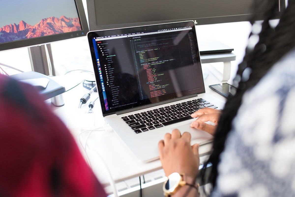 A woman sitting at a desk writing code on a laptop computer. A Day in the Life of a Web Developer