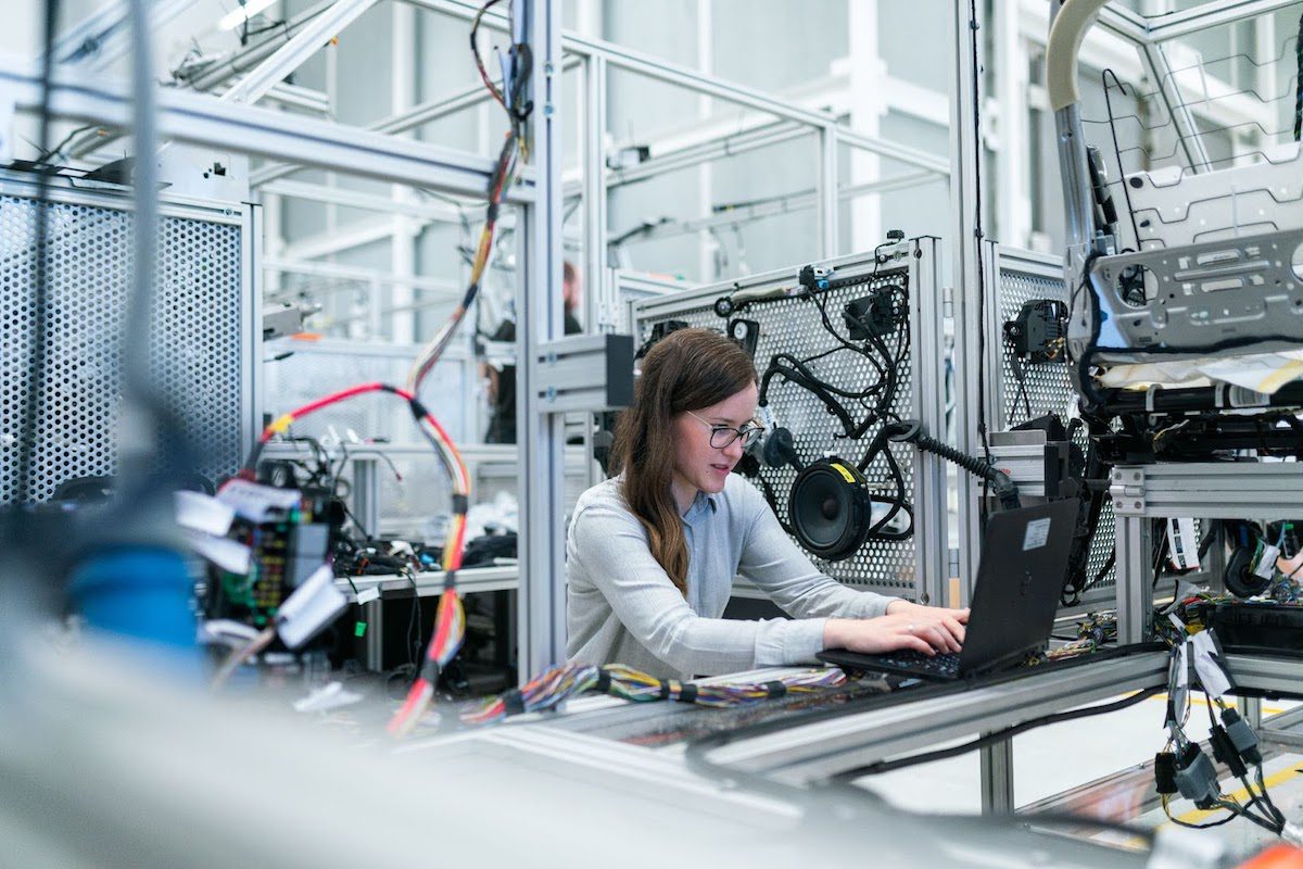 A female engineer working on a laptop in a workshop setting with wires and speakers.  A Day in the Life of an Engineer