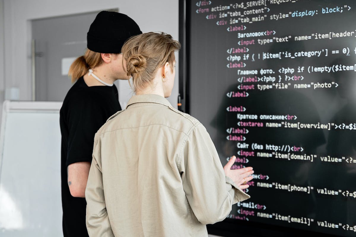 Two people analyzing computer code on a screen.  Companies That Use Laravel