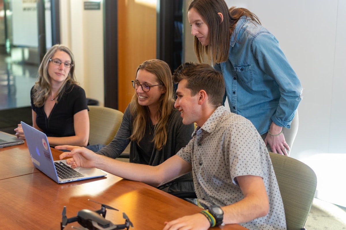  Four employees sitting around a table looking at a laptop. Companies That Use Django