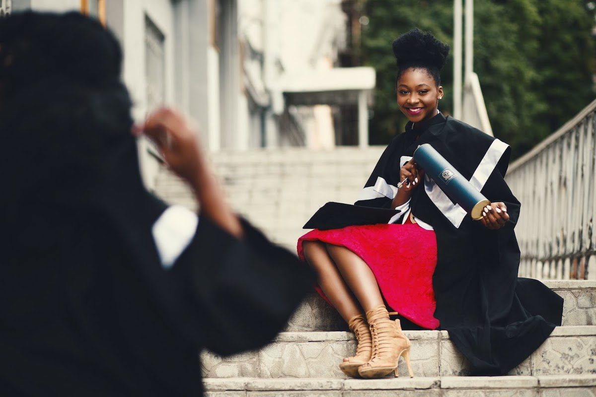  A college graduate sitting on the stairs of her institution.  Trends In College Career Services