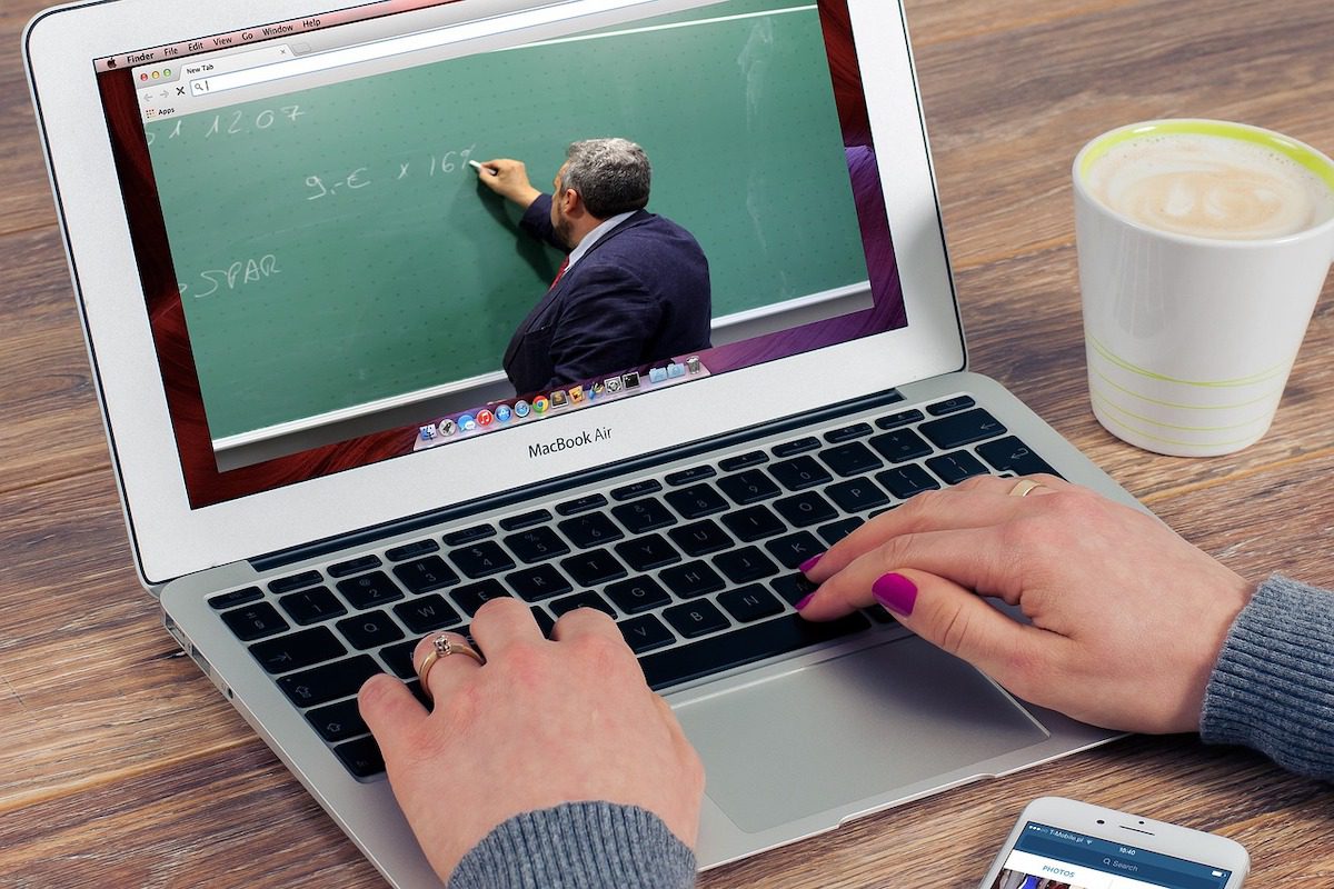 A person with their hands on the keyboard of a Macbook showing an online video lesson. Trends in Education in 2022