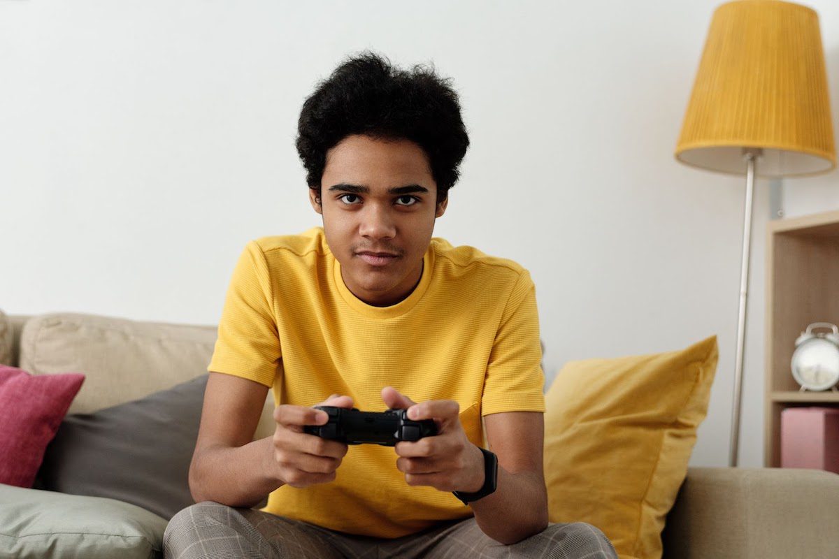 A 13-year-old boy dressed in a yellow shirt playing video games. Online Jobs For 13 Year Olds