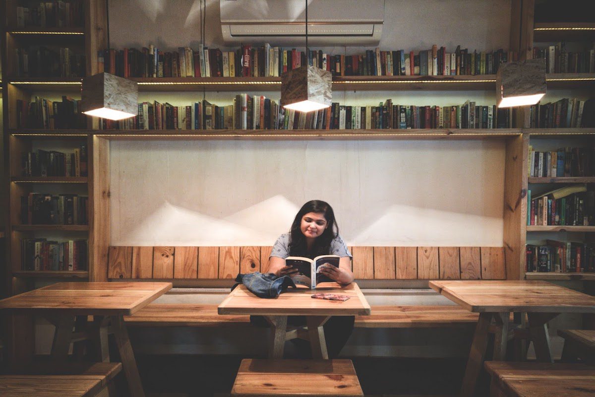 A woman reading at a table in a library.