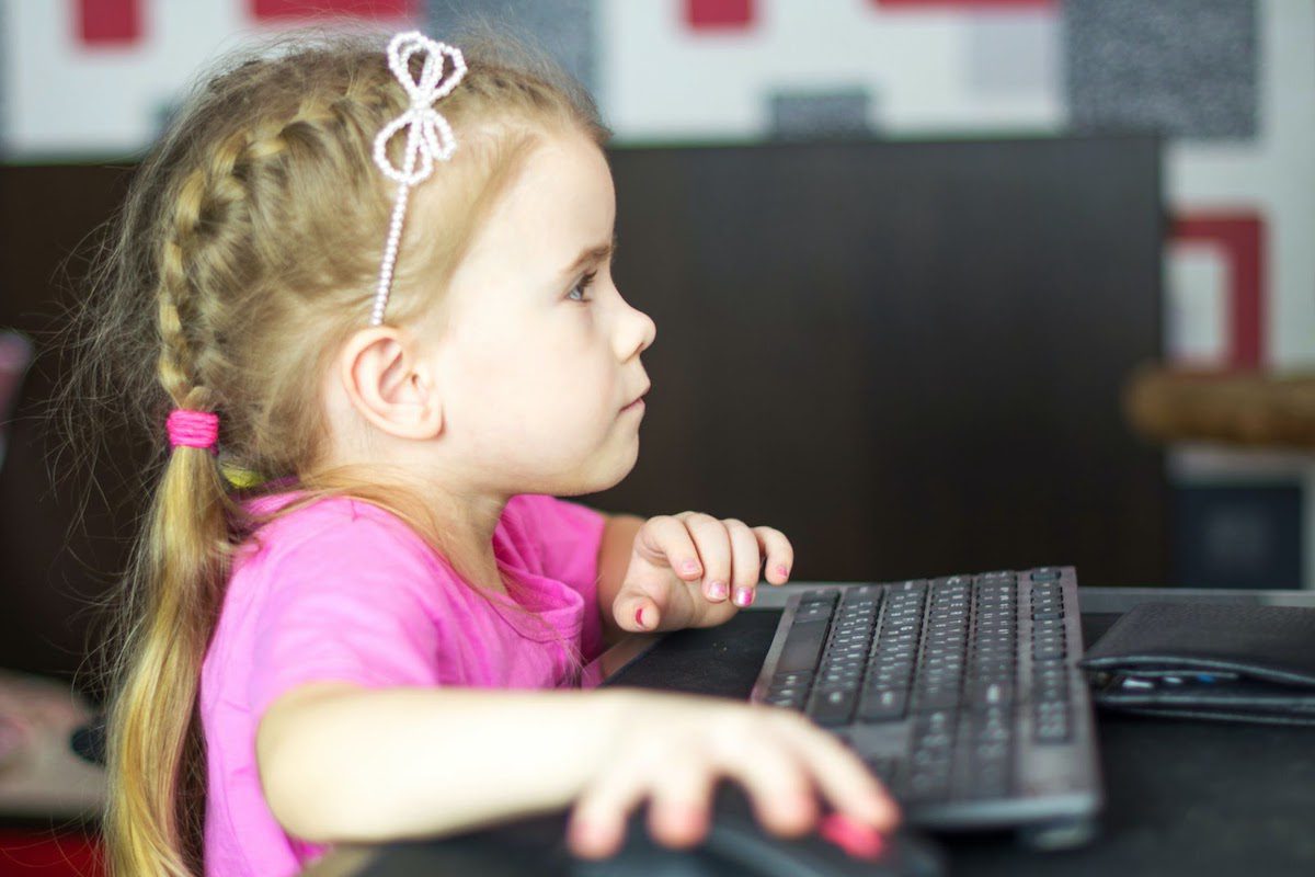 Little girl sitting in front of a keyboard.