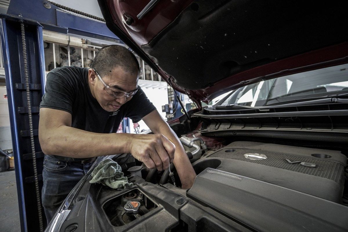 An auto mechanic replacing the oil in an engine.