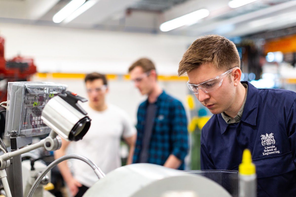 Engineering students in an engineering workspace utilizing equipment for a project. 