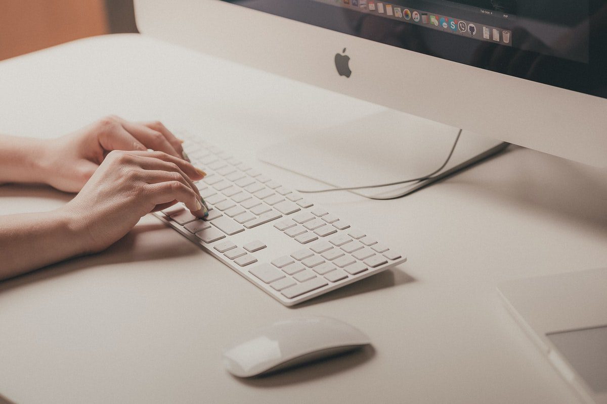 Hands typing on an ergonomic keyboard in an efficient workspace.