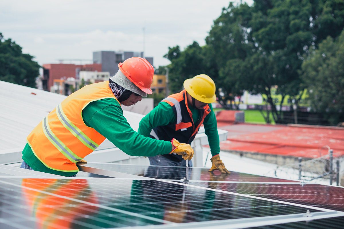 Two renewable energy environmental workers installing solar panels. 