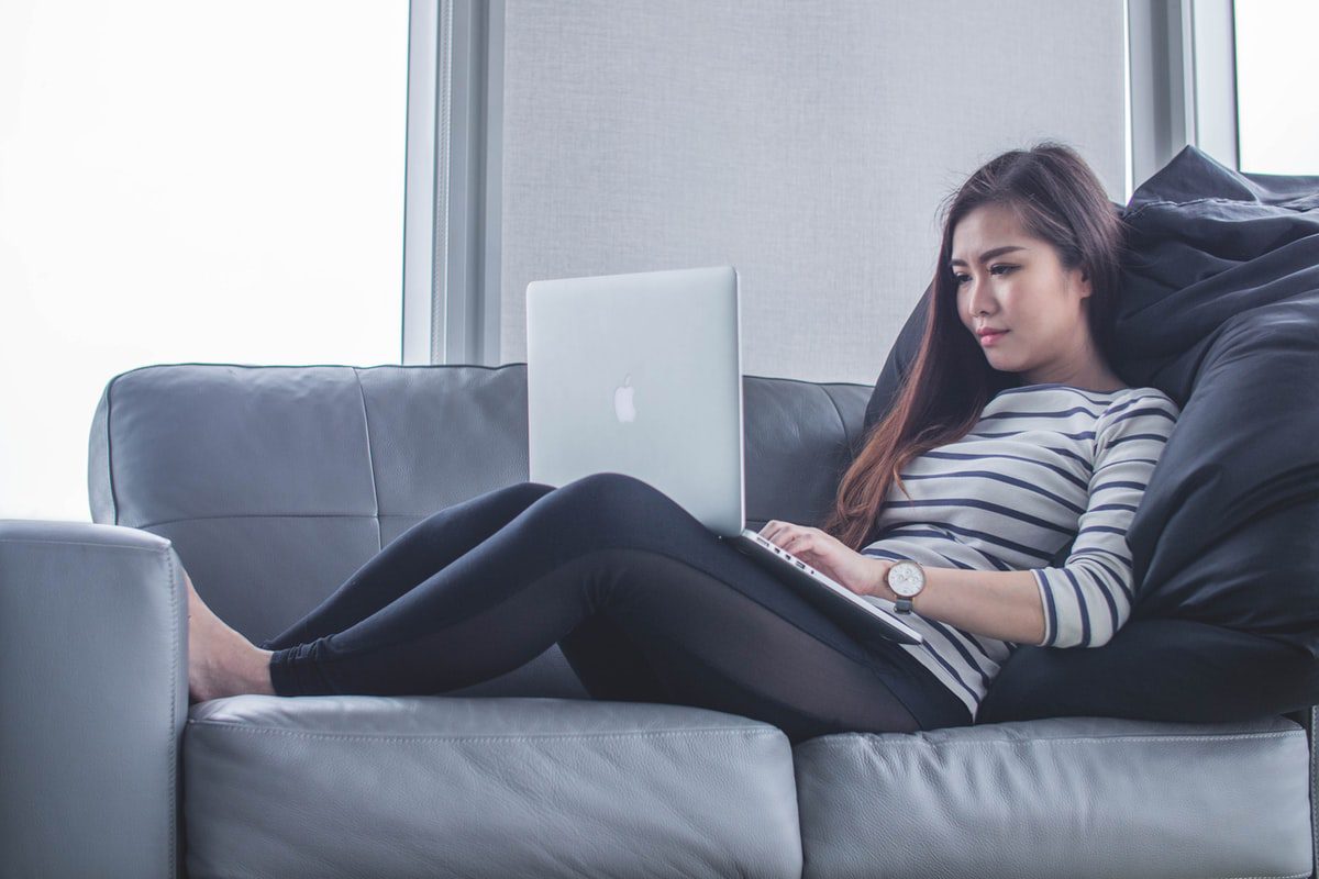 Young woman sitting on a sofa working on her laptop