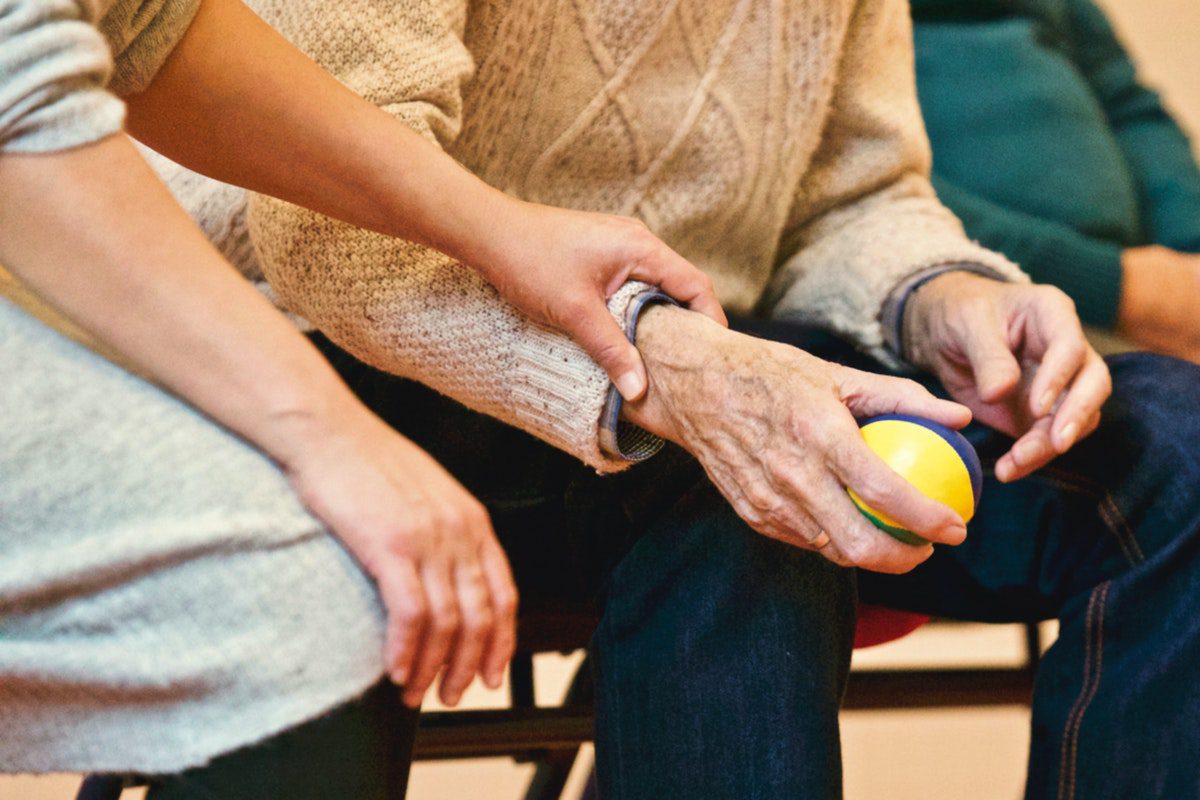 An elderly man clutches a stress ball during a group therapy session