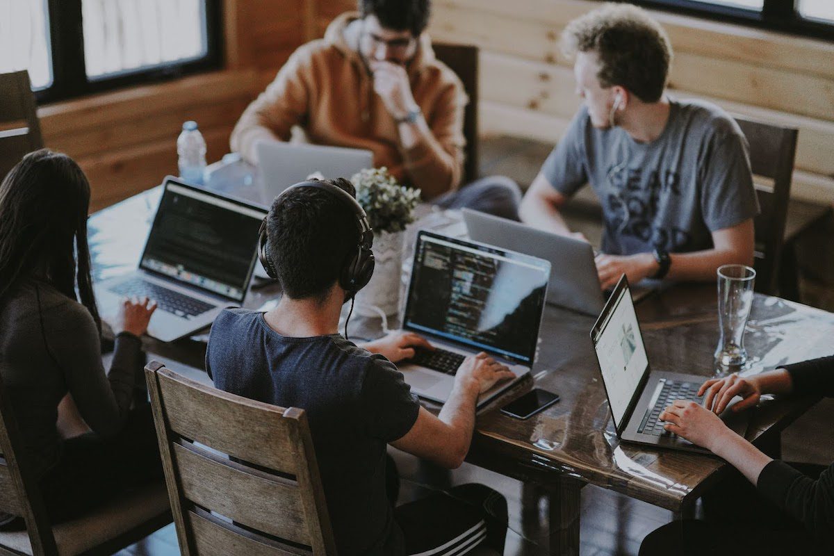 Group of customer care specialists gathering in an office, with their laptops, having a meeting.