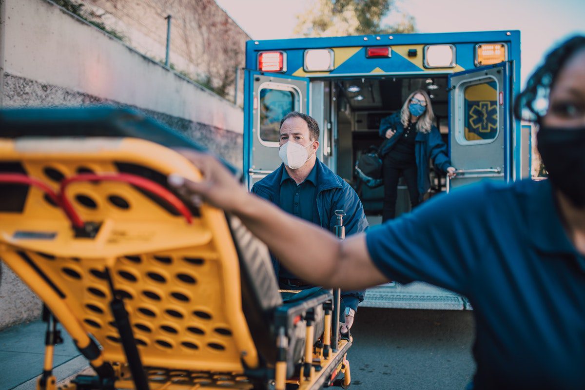 paramedics standing close to an ambulance while holding a stretcher