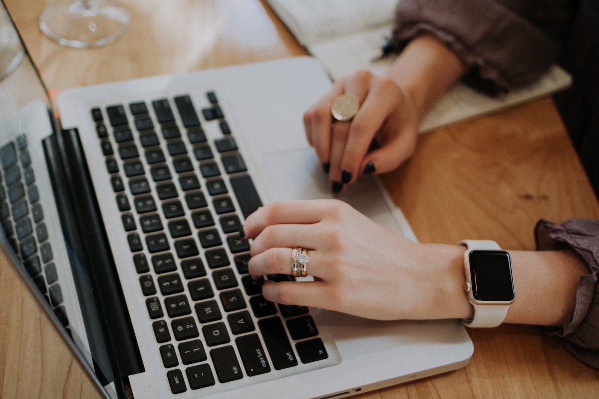 A person typing on a laptop to ask for bootcamp sponsorship from her employer.