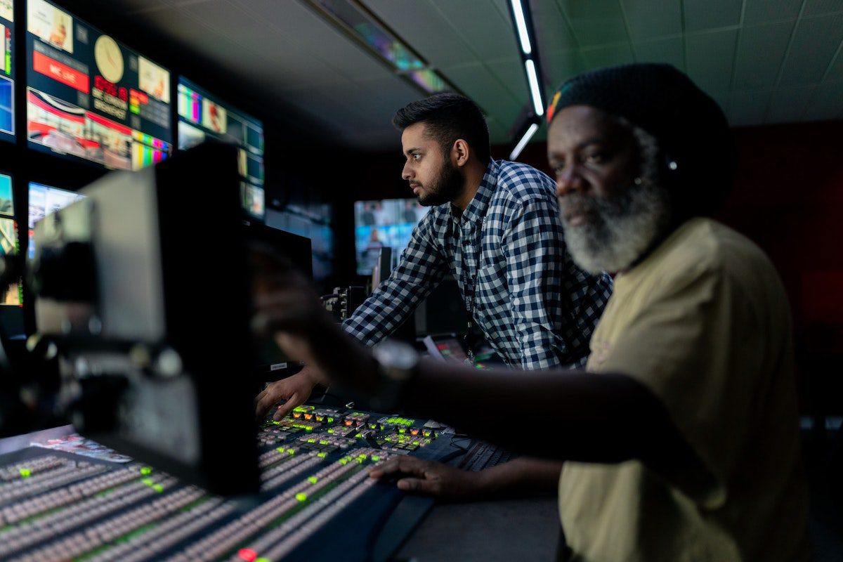 Two tech workers looking at an array of monitors.